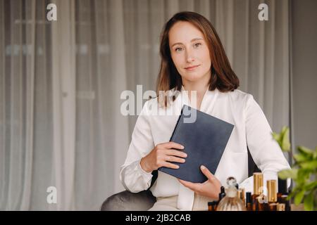 portrait d'une jeune fille souriante assise dans un fauteuil. Un aromathérapeute dans un chemisier blanc est assis dans le bureau. Banque D'Images