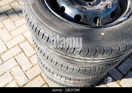 Vue de dessus des pneus d'été empilés sur des jantes en acier noir. Mise au point sélective. Les roues de voiture sont prêtes pour le remplacement saisonnier. Banque D'Images