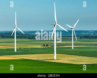 Une image étonnante de trois éoliennes offshore fournissant de l’électricité verte parallèlement à des pratiques agricoles efficaces Banque D'Images