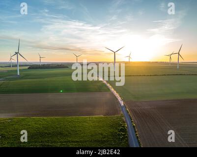 Prise aérienne de haut en bas sur un coucher de soleil, il y a des moulins à vent et un champ de cultures. secteur des énergies propres et renouvelables. Banque D'Images