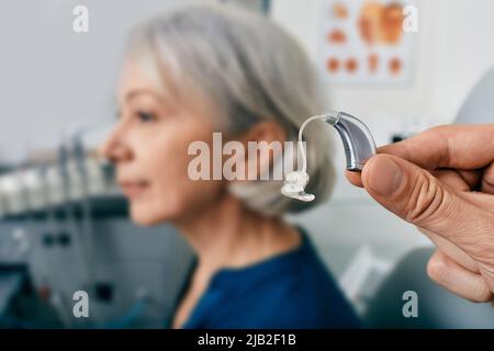 Gros plan de l'aide auditive près de l'oreille du patient senior à la clinique d'audiologie. Solutions auditives, prothèses auditives Banque D'Images