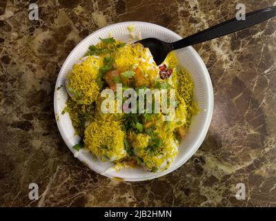 Vue de dessus de Dahi sev puri servi dans un bol jetable et placé sur un comptoir en marbre. Banque D'Images