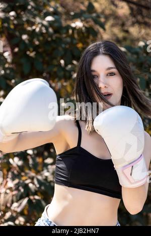 boxeur jeune femme avec gants blancs dans un parc Banque D'Images