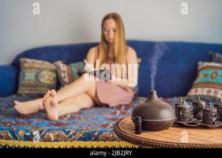 Concept d'aromathérapie. Diffuseur et humidificateur d'huile essentielle à ultrasons en bois électrique. Diffuseur d'arôme ultrasonique pour la maison. Femme se reposant à Banque D'Images