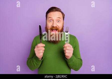 Portrait de l'homme fou positif tenir le couteau de fourche ouvert bouche ne peut pas attendre la nourriture isolée sur fond violet de couleur Banque D'Images