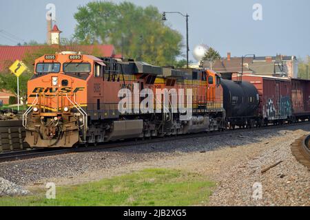 Fort Madison, Iowa, États-Unis. Deux locomotives Burlington Northern Santa Fe conduisent un train de marchandises au-delà des plates-formes de la gare Amtrak. Banque D'Images