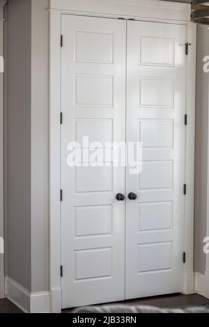 Une paire ou un ensemble de deux placard d'entrée de hall peint en blanc a fermé cinq portes de panneau dans une nouvelle maison de construction avec des murs grèges Banque D'Images