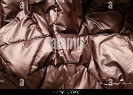 veste matelassée en bronze brun pour femme comme arrière-plan, fond de tissu léger et doux d'une veste matelassée, veste matelassée pour l'hiver Banque D'Images