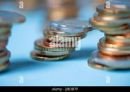 Pièces de monnaie empilées sur fond bleu. Pièces en euros de l'Union européenne. Les devises et les espèces s'empilent dans les tours Banque D'Images