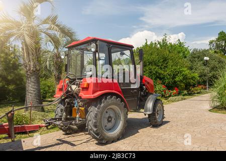 Tracteur rouge dans le parc de la ville, service d'entretien du territoire Banque D'Images