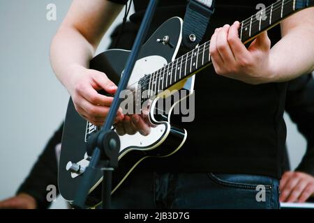 Guitare électrique chromée noire et gros plan des mains du guitariste Banque D'Images