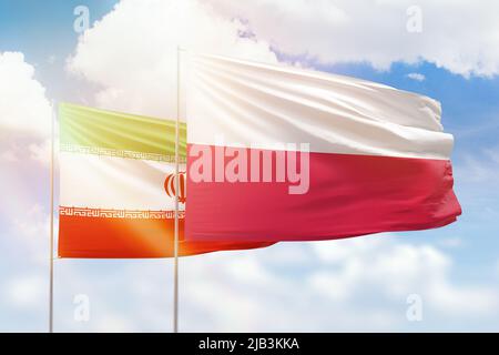 Ciel bleu ensoleillé et drapeaux de la pologne et de l'iran Banque D'Images