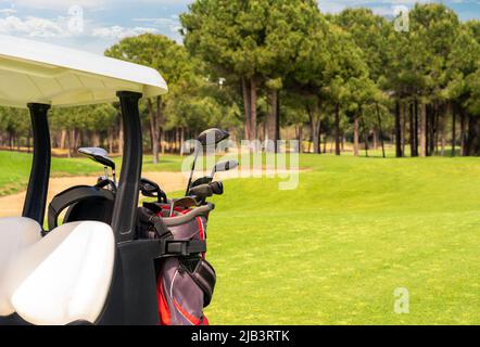 Ensemble d'équipement de golf dans des sacs de golf à l'arrière d'une voiturette de golf sur un beau terrain de golf Banque D'Images