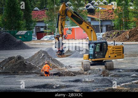 Deux ouvriers non reconnaissables travaillant avec une pelle hydraulique - préparer le terrain pour des fondations en béton sur le site d'un nouveau bâtiment Banque D'Images