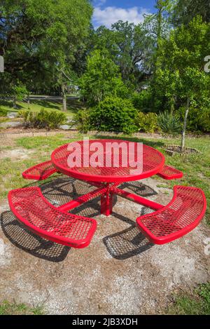 Table de pique-nique rouge dans un parc public de petite ville dans le centre-nord de la Floride. Banque D'Images