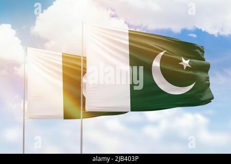 Ciel bleu ensoleillé et drapeaux du pakistan et du pakistan Banque D'Images