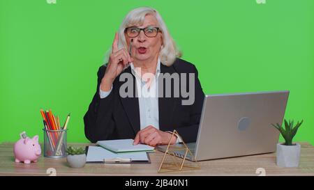 Une femme d'affaires chevronné qui prend des notes, écrit ses pensées avec un stylo dans son carnet de notes, liste de tâches, bonne idée sur le lieu de travail au bureau. Femme âgée dans un studio de clé à chroma vert Banque D'Images