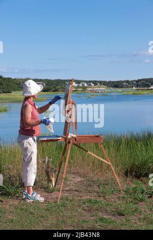 Femme artiste peignant le pittoresque Duck Creek sur Cape Cod à Wellfleet, Massachusetts, Banque D'Images
