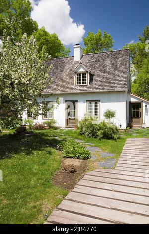 Ancienne maison de style caniana vers 1886 avec revêtement en stuc blanc et toit en bardeaux en cèdre au printemps. Banque D'Images