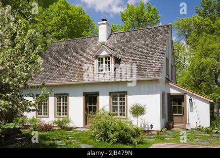 Ancienne maison de style caniana vers 1886 avec revêtement en stuc blanc et toit en bardeaux en cèdre au printemps. Banque D'Images