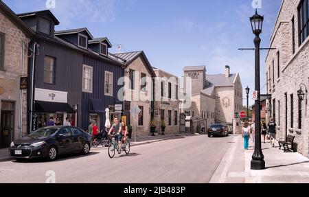 Elora, Ontario, Canada - 05 15 2022 : vue estivale le long de la rue Mill Ouest avec rangée de maisons anciennes de deux étages et édifice Elora Mill de 1832 po Banque D'Images