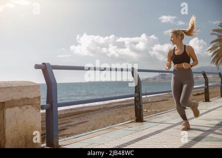 Bonne jeune femme courir le long de la belle mer Banque D'Images