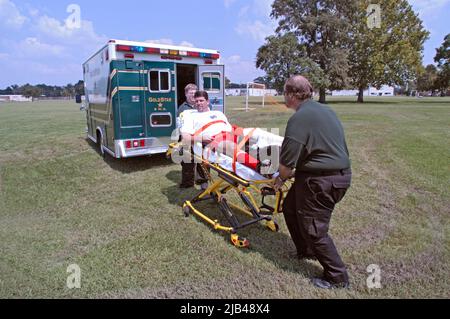 Joueur de football, homme adulte avec une jambe cassée est mis en ambulance sur brancard par les médecins pendant le jeu qui a été co-ed, les hommes et les femmes dans les équipes Banque D'Images