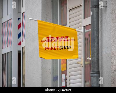 DHL Paketshop dans la ville. Un petit drapeau jaune est suspendu à l'extérieur d'un magasin. Le logo signifie que les gens peuvent expédier et recevoir des colis Banque D'Images