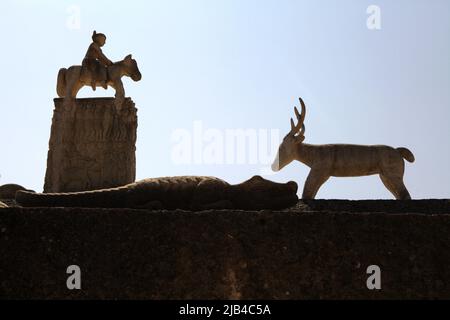 La sculpture d'un homme à cheval et d'une figure de cerf est silhouetée dans un ciel bleu vif; photographiée dans un cimetière traditionnel du village traditionnel de Poriliu à Kambera, à l'est de Sumba, à Nusa Tenggara, en Indonésie. Banque D'Images