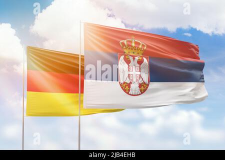 Ciel bleu ensoleillé et drapeaux de la serbie et de l'allemagne Banque D'Images