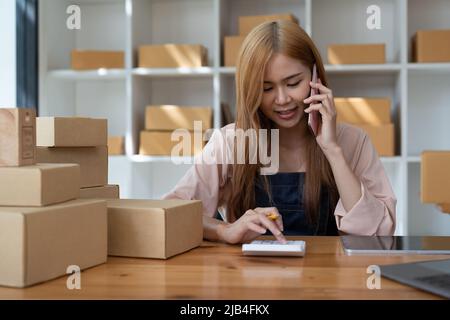 Laisser tomber le propriétaire d'affaires d'expédition parler sur le téléphone mobile et de prendre la commande. Femme entrepreneur travaillant au bureau à domicile confirmant la commande au téléphone. Banque D'Images