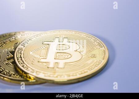 Gros plan de trois bitcoins d'or sur fond plat. Banque D'Images