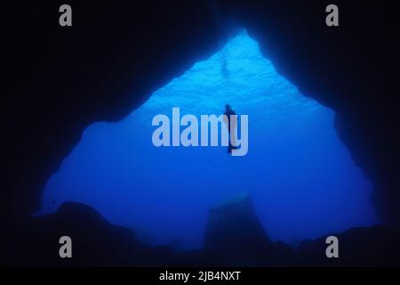 Plongeur flottant en eau libre devant une grande entrée de grotte sous-marine, mer Méditerranée, Majorque, Espagne Banque D'Images