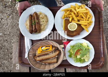 Bratwurst avec de la choucroute et du pain et du cordon bleu avec des frites servis sur un plateau dans un restaurant de jardin, Franconia, Bavière, Allemagne Banque D'Images