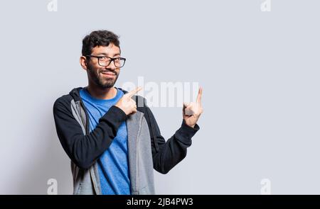 Personne souriante pointant les doigts sur le côté, homme souriant recommandant quelque chose avec les doigts sur un arrière-plan isolé, personnes isolées pointant les doigts Banque D'Images