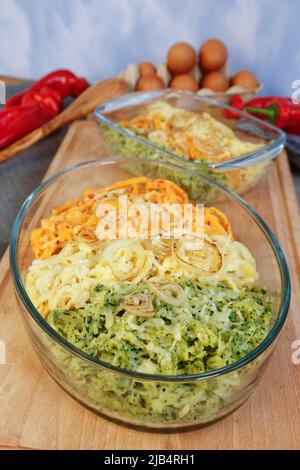 Cuisine souabe, cassolette spaetzle, trois types de spaetzle cuits au fromage, spaetzle classique, aux épinards et au paprika rouge, oignon pelé Banque D'Images