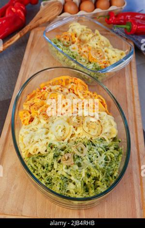 Cuisine souabe, cassolette spaetzle, trois types de spaetzle cuits au fromage, spaetzle classique, aux épinards et au paprika rouge, oignon pelé Banque D'Images