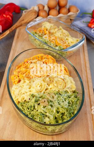 Cuisine souabe, cassolette spaetzle, trois types de spaetzle cuits au fromage, spaetzle classique, aux épinards et au paprika rouge, oignon pelé Banque D'Images