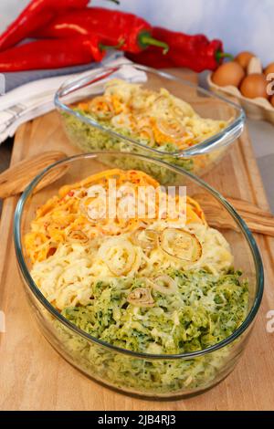 Cuisine souabe, cassolette spaetzle, trois types de spaetzle cuits au fromage, spaetzle classique, aux épinards et au paprika rouge, oignon pelé Banque D'Images