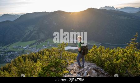 Randonneur debout sur le chemin de randonnée entre les pins de montagne, vue sur le paysage de montagne avec Pillersee, descente de Heimkehrerkreuz, Nuaracher Hoehenweg Banque D'Images
