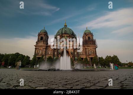 Vue extérieure de la cathédrale de Berlin ou du Dom, avec fontaine visible et quelques personnes en mouvement flous suspendus devant le bâtiment. Belle soirée d'été. Banque D'Images