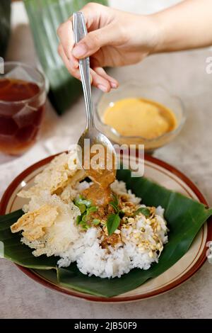 Verser le Tumpang de Sambal dans l'assiette de thé avec du riz et des légumes frais. SAmbel Tumpang est un plat typique de Java central et de Java oriental fabriqué à partir de Tempe Boso Banque D'Images