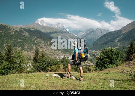 Hiker homme se sur la falaise contre le sommet d'une montagne. L'homme a un sac à dos et bâtons de marche. Les randonnées en montagne. Copy space Banque D'Images