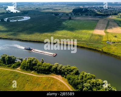 Towboat transporte la barge avec le sable le long de la rivière tranquille Banque D'Images