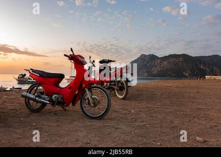 Matin sur la plage dans le village de Cirali, des scooters rouges se tiennent sur la plage., promenade en scooter le matin. Paysages du sentier lycien. Banque D'Images