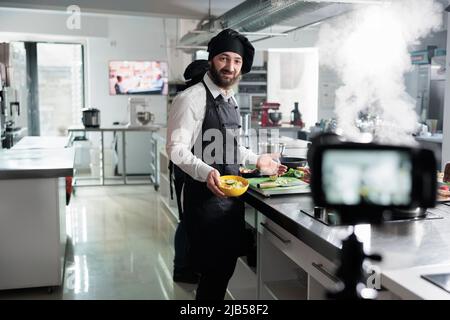 Chef cuisinier qui se présente au processus de préparation du plat par caméra tout en filmant pour le cours culinaire. Expert en gastronomie de restaurant cuisine professionnelle enregistrement de la cuisine alimentaire pour le tutoriel Internet. Banque D'Images