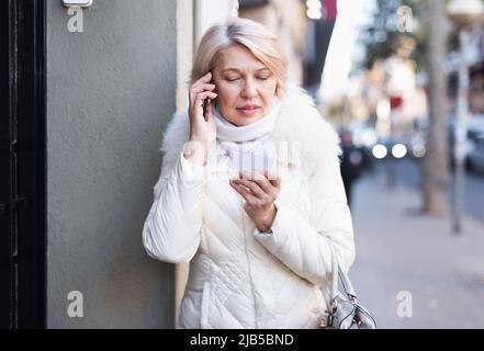 Femme parlant au téléphone près de la porte et tenant le papier Banque D'Images