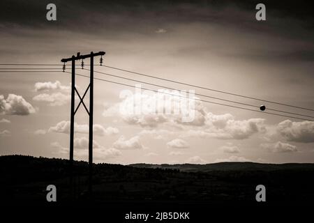 Silhouette de lignes électriques contre un ciel nuageux au crépuscule dans un paysage rural, Auvergne, France, Europe Banque D'Images