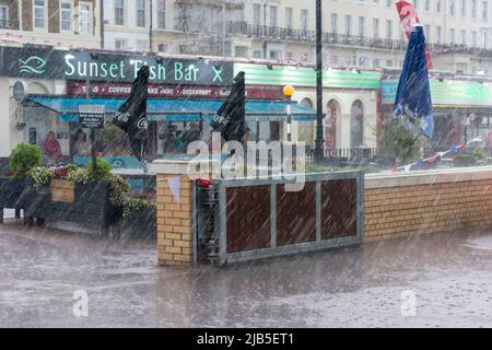 Une descente gâte l'après-midi à la baie de Herne avec la pluie qui descend sur la promenade, forçant les gens à s'abriter. Banque D'Images