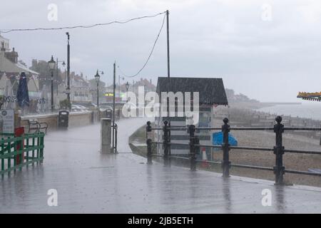 Une descente gâte l'après-midi à la baie de Herne avec la pluie qui descend sur la promenade, forçant les gens à s'abriter. Banque D'Images